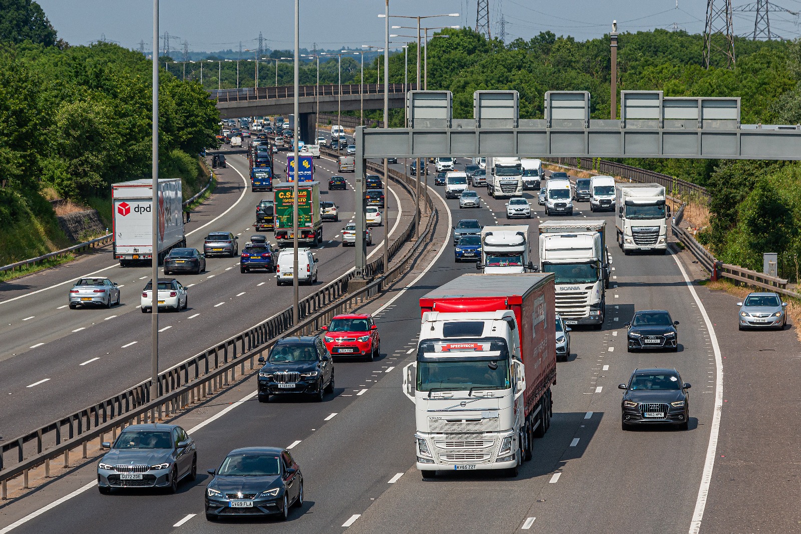 HGV vehicles driving on a busy UK motorway approaching an urban area